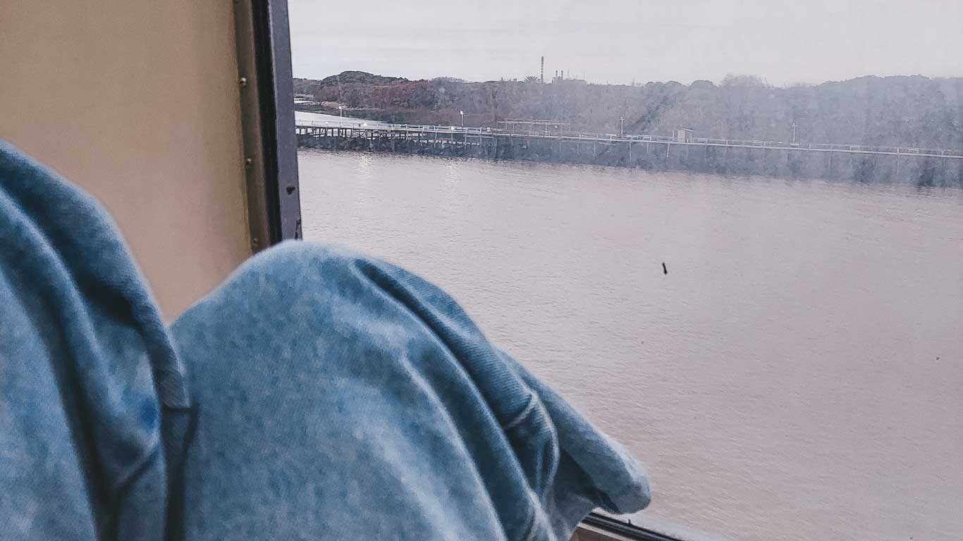 A passenger enjoys the view of the Rio de la Plata from a ferry, showing a serene journey as the best way to get from Buenos Aires to Montevideo.