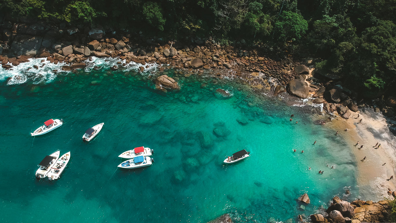 Aerial view of Praia do Caxadaço in Ilha Grande, with a boat anchored over the crystal-clear waters