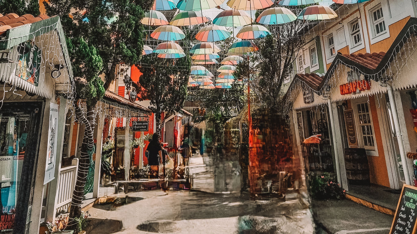 Penedo town center, with colorful shops and a street covered with vibrant umbrellas.