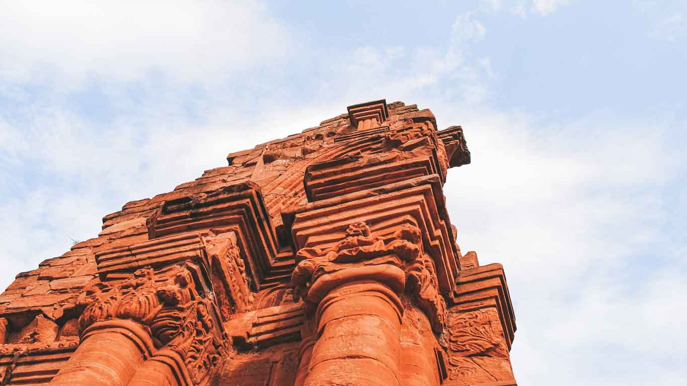 High angle view of an imposing red stone structure at the ruins of San Ignacio Miní, Misiones, Argentina. The image highlights the carved architectural details and majesty of the construction against a partly cloudy sky.