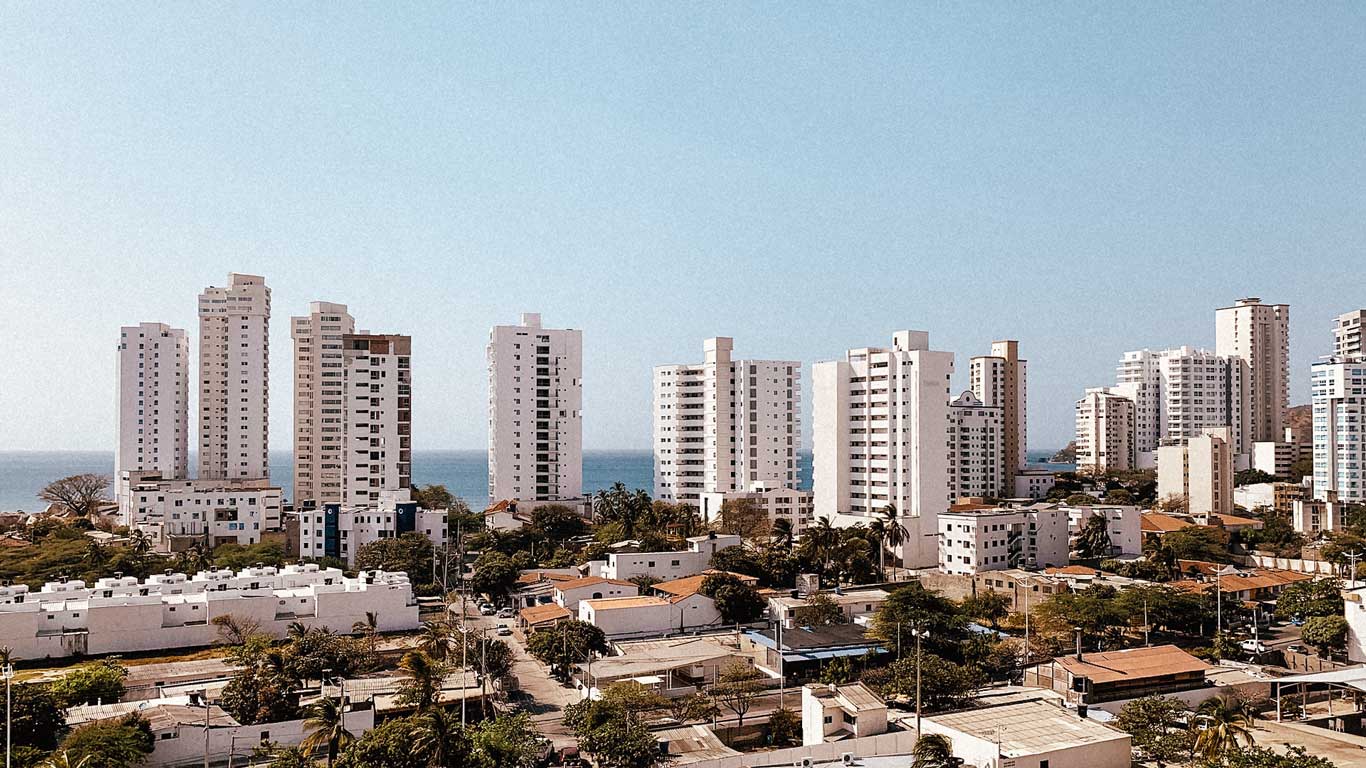 Panoramic view of tall buildings near the beach in El Rodadero, Santa Marta. The sea appears in the background, surrounded by modern constructions and a light blue sky, in the best neighborhood to stay in Santa Marta.