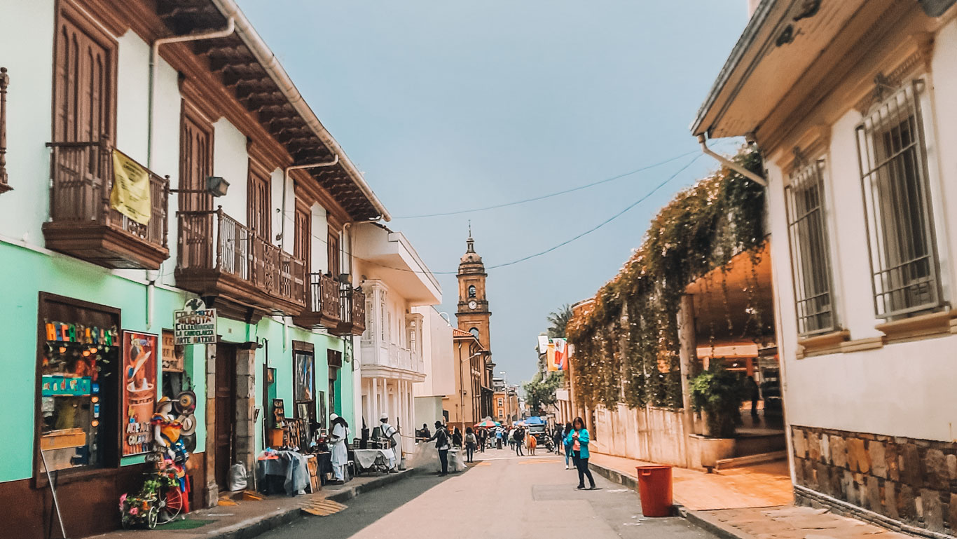 A charming street in Bogotá’s La Candelaria neighborhood, this is a great option for where to stay in Bogotá. The cobblestone street is bustling with pedestrians, street vendors, and a historic clock tower in the background. 