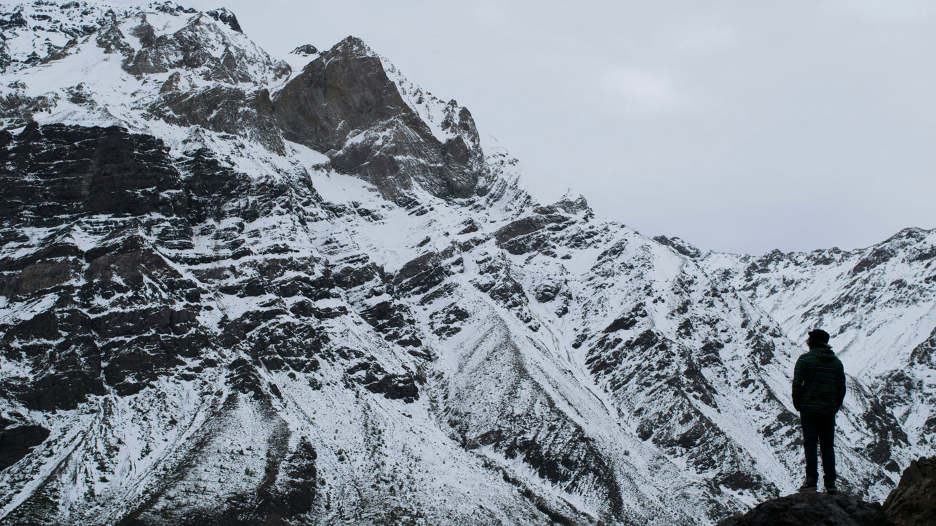 cajon-del-maipo-chile A lone hiker looks up at the rugged, snow-covered peaks of Cajón del Maipo, a popular winter escape near Santiago, Chile, during the snow season.