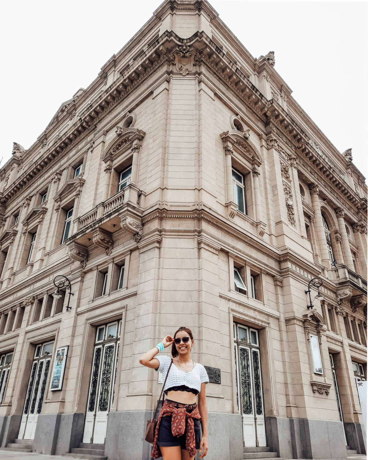 colon-theater-buenos-aires-2 A woman smiles in front of the neoclassical Teatro Colón, one of the most beautiful opera houses in the world and a top cultural experience among things to do in Buenos Aires.