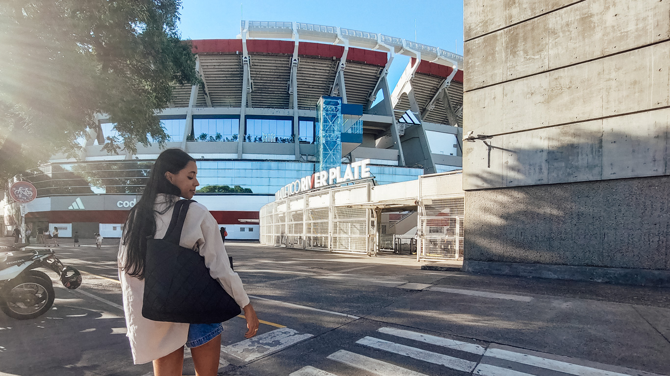 river-plate A woman walks toward the entrance of Estadio Monumental Antonio Vespucio Liberti, home of River Plate, with the stadium's red and white exterior visible in the background.
