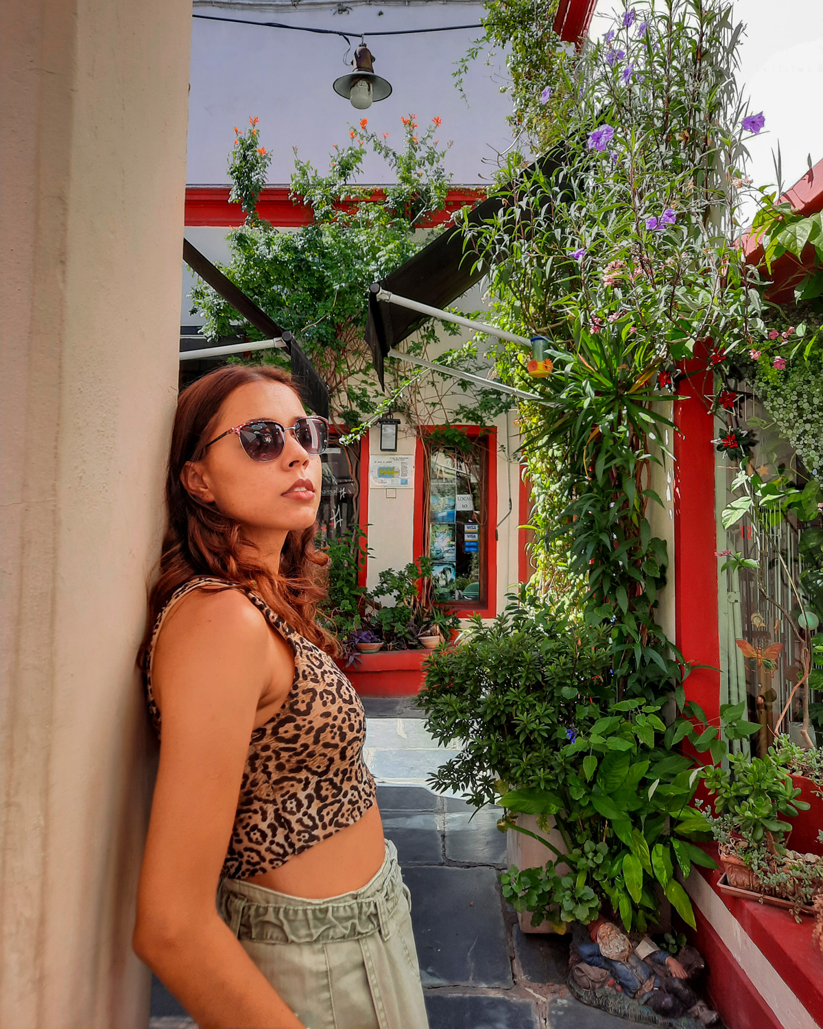 salar-french-1 Woman leaning against a wall in a charming courtyard filled with lush plants and colorful decor, one of the photogenic spots.