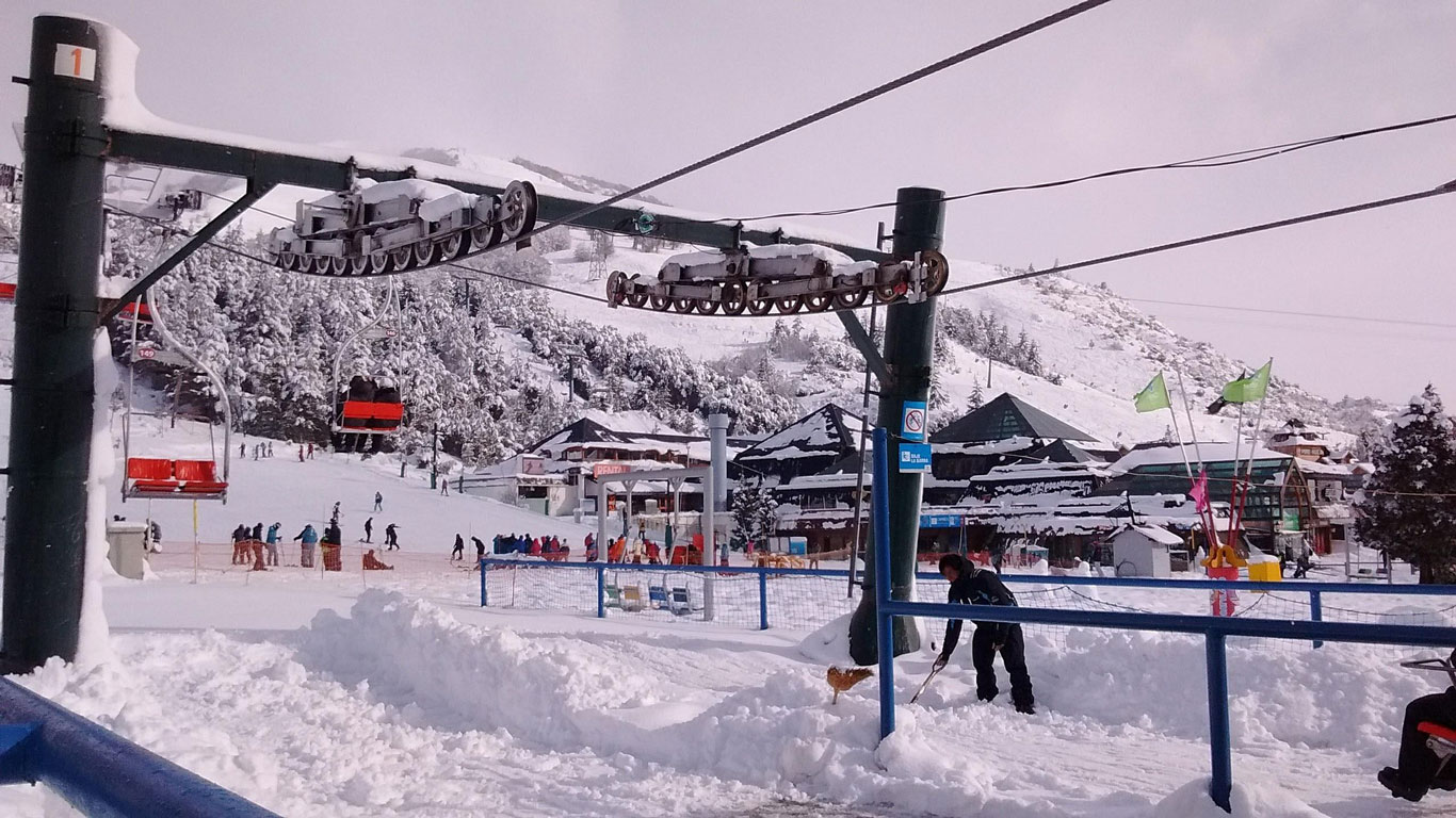 ski-lesson-in-bariloche A ski school scene at the base of Cerro Catedral with instructors guiding beginners, as chairlifts and snow-covered buildings add to the bustling winter atmosphere.