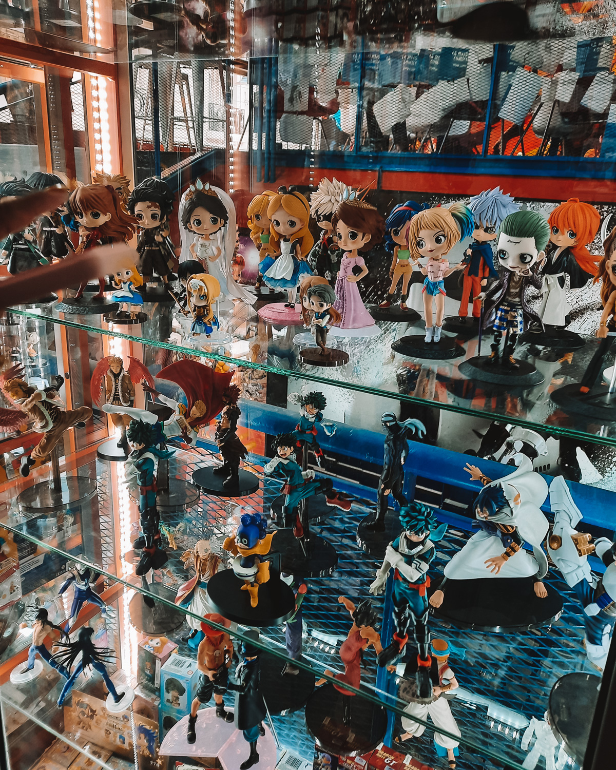 La-Revisteria-Buenos-Aires Shelves filled with colorful anime and manga figurines inside La Revistería in Buenos Aires, showcasing characters from series like Sailor Moon, My Hero Academia, and Dragon Ball. A person’s hand is visible reaching toward the display.