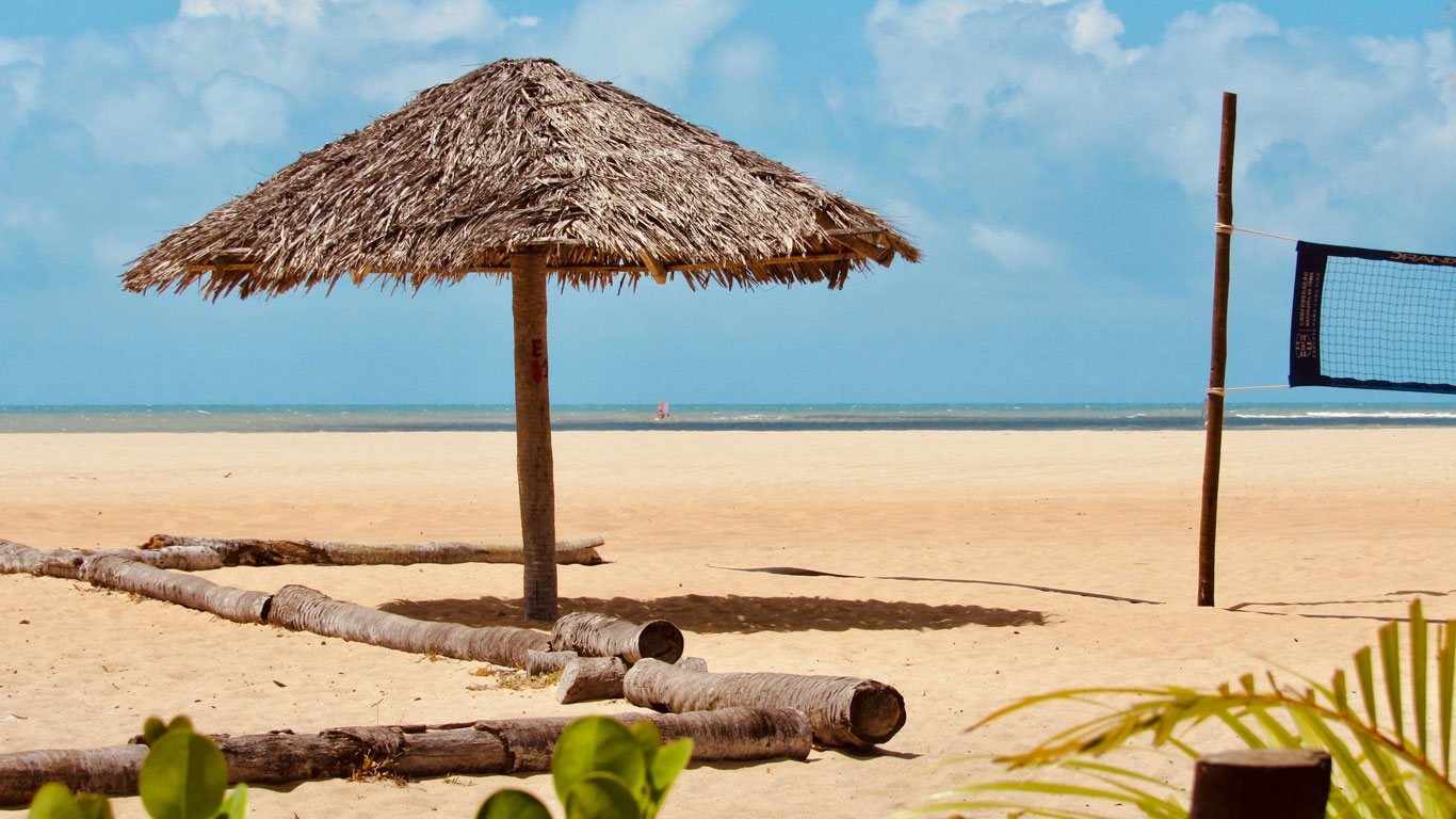 Thatched hut on a quiet beach with volleyball net and views of the blue sea — a typical setting for where to stay in São Miguel do Gostoso, perfect for relaxing in comfort by the sea.