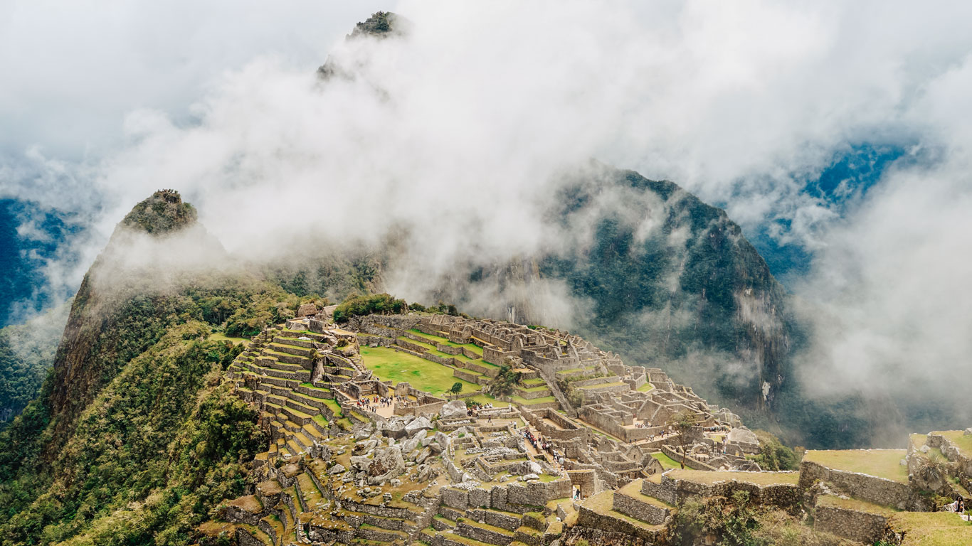 A panoramic view of Machu Picchu surrounded by misty mountain peaks, showcasing the iconic stone ruins and terraced landscape, perfect visual context for travelers researching where to stay in Machu Picchu.