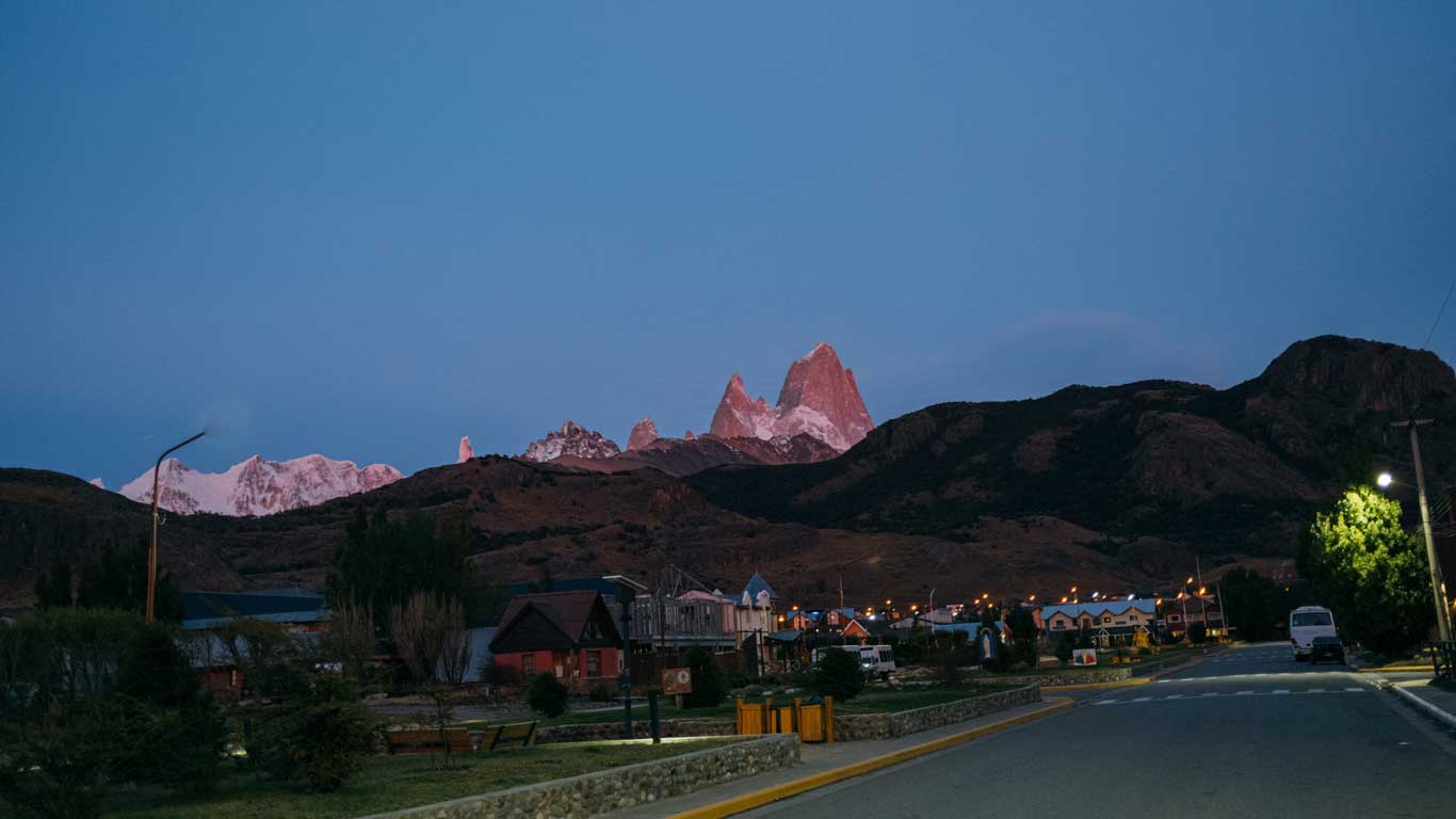 The town of El Chaltén at dusk with Mount Fitz Roy glowing pink in the background. This scenic stop is often included in tours in El Calafate for those exploring Los Glaciares National Park.